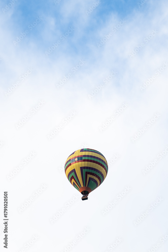 Fototapeta premium Colorful hot air balloon floating across blue sky