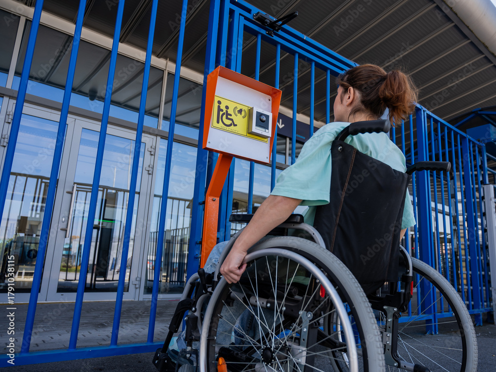 Obraz premium A woman in a wheelchair uses a touch-sensitive Braille help button.. 