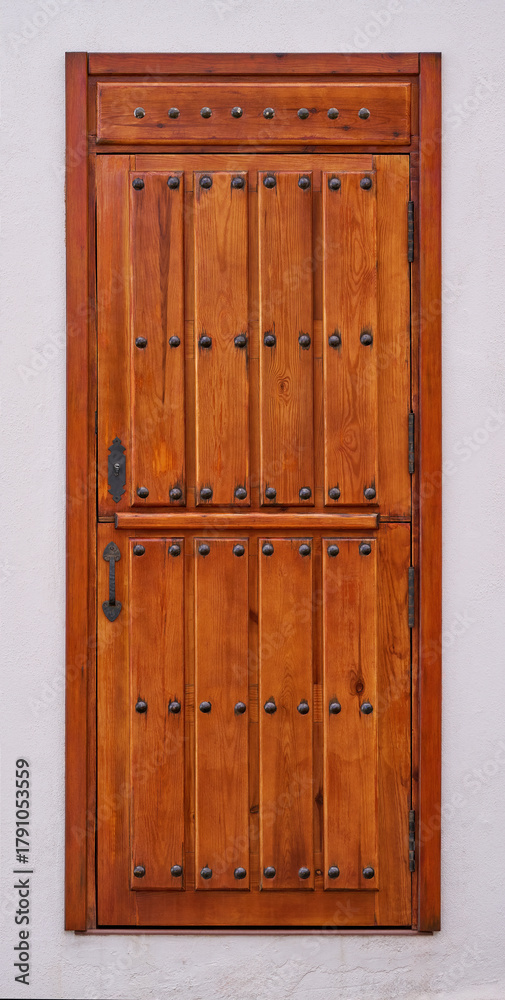 Fototapeta premium Braune kanarische Holztür mit großen Ziernägeln in einer weißen Wand in El Hierro, Kanarische Inseln