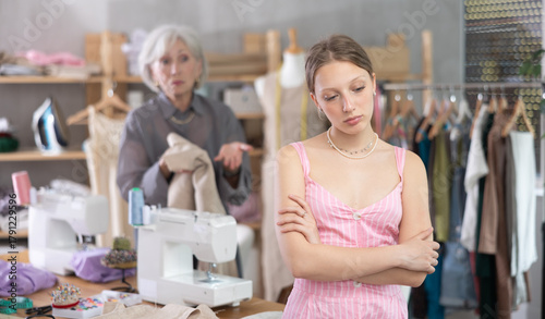 Photos Mature dressmaker scolds assistant with displeasure at work in a sewing workshop