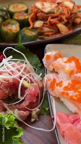 Hand using chopsticks pick Sushi and Sashimi rolls on the glass table. Fresh made Sushi set with salmon, prawns, wasabi and ginger. Traditional Japanese cuisine. Sushi buffet bar, Food Concept