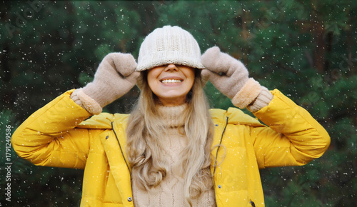 Winter portrait of happy cheerful woman having fun in hat against Christmas tree in forest