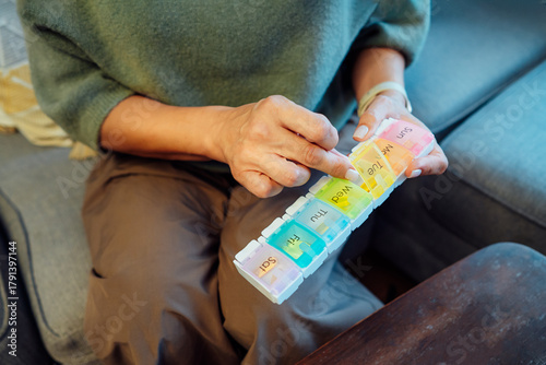 No face Middle age female holds pill box in her hands. Woman in menopause taking daily dose of minerals for skin and health care, boost metabolism. Vitamin A, D, C deficiency prevention treatment.