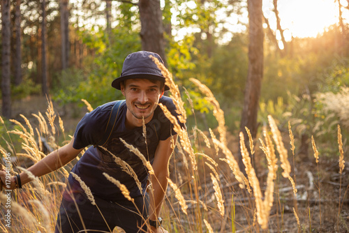 Handsome young caucasian man in the forest woods with shining spikelets in black panama
