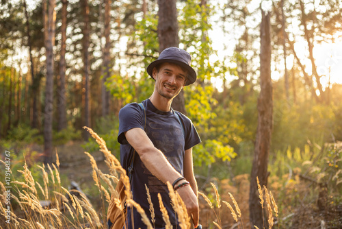 Handsome young caucasian man in the forest woods with shining spikelets in black panama