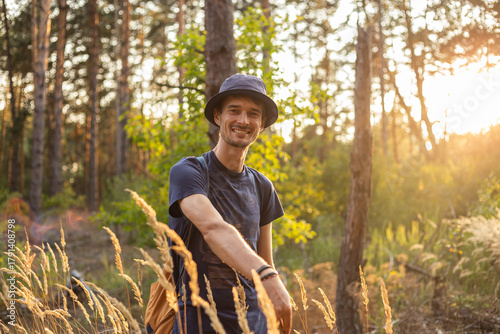 Handsome young caucasian man in the forest woods with shining spikelets in black panama