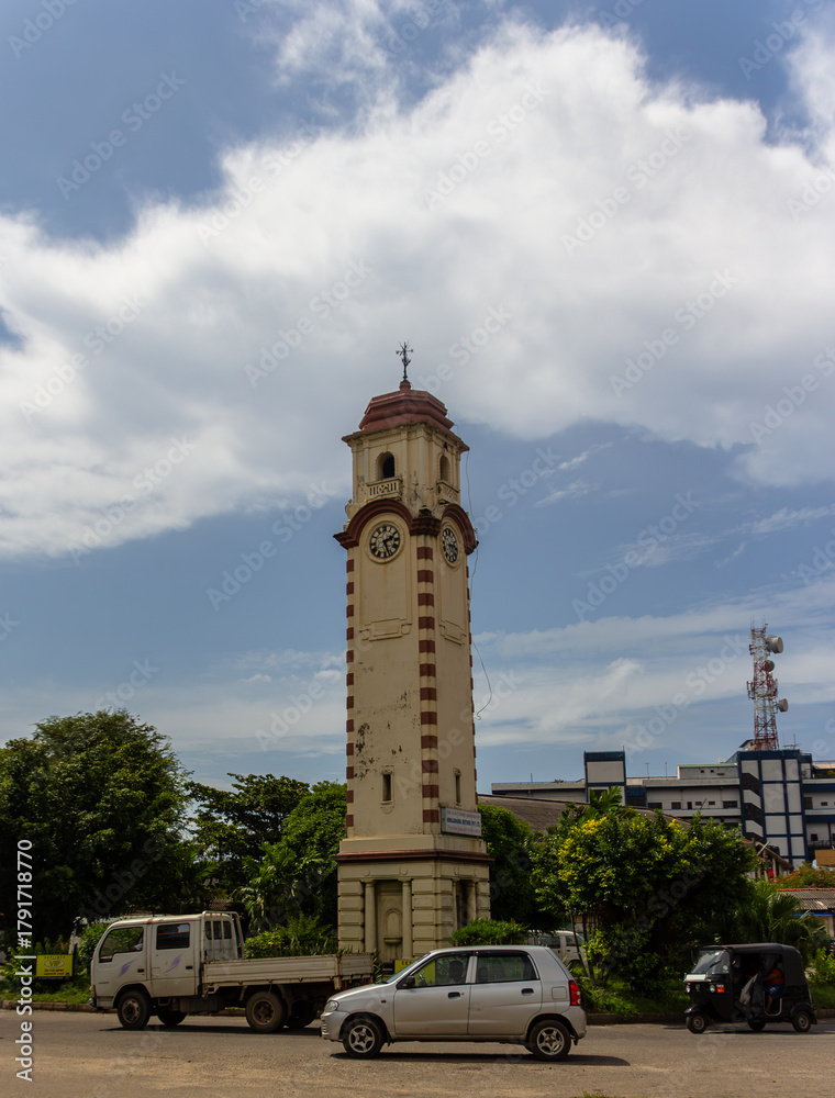 Fototapeta premium Vertical view of the historic Khan Clock Tower landmark with street traffic under a cloudy sky in Colombo, Sri Lanka.