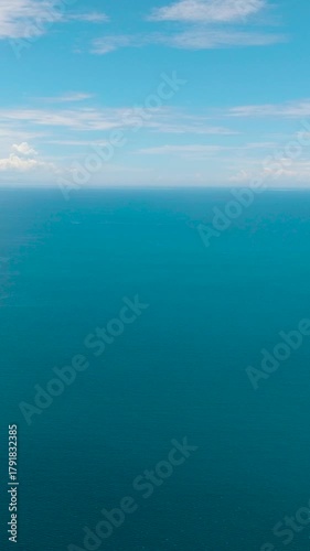 Flight over the blue sea and sky with clouds. Mindanao, Philippines. Vertical video.