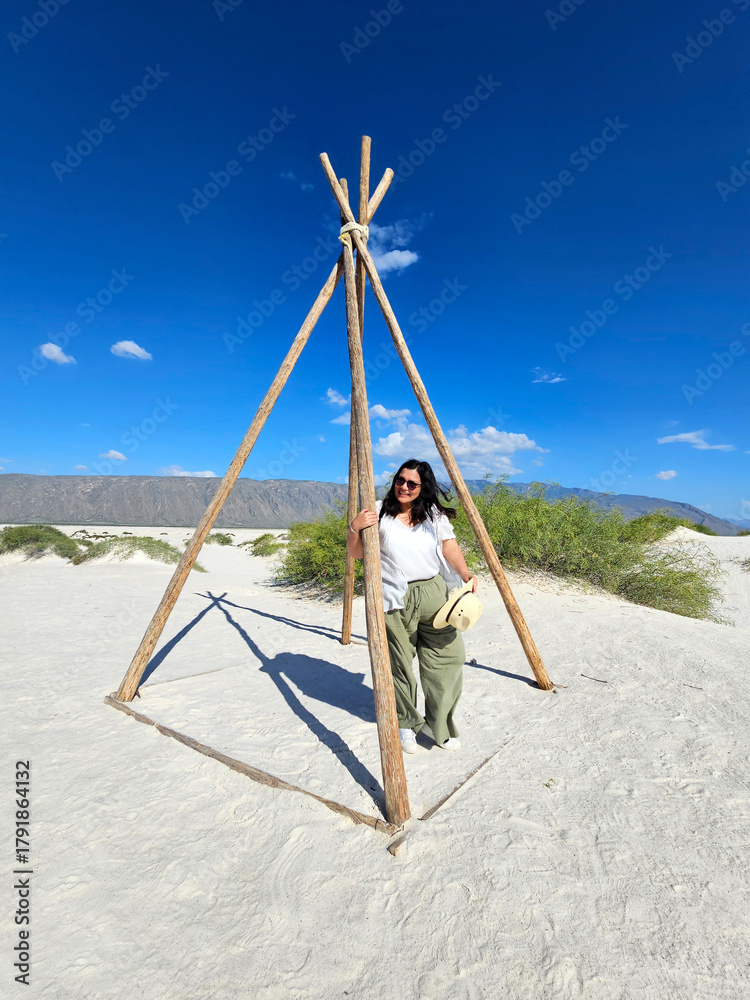 Fototapeta premium Brunette Latina adult woman walks through the gypsum dunes in the middle of the white desert enjoying the freedom and fullness of feeling nature