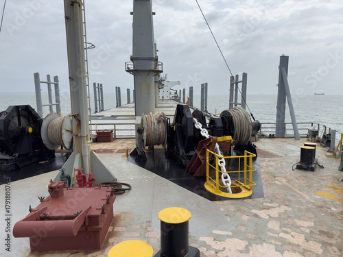 Forward mooring station of cargo ship showing windlass, mooring winches, ropes, and anchor chain. 2