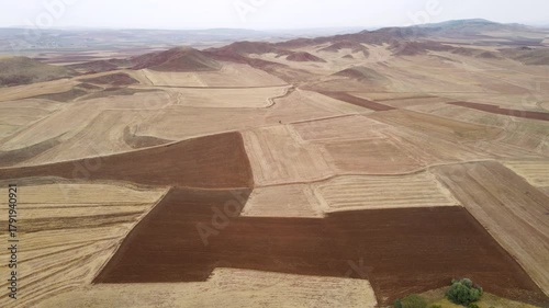Aerial footage of large agricultural lands with corn, wheat and sunflower fields and red mountains.