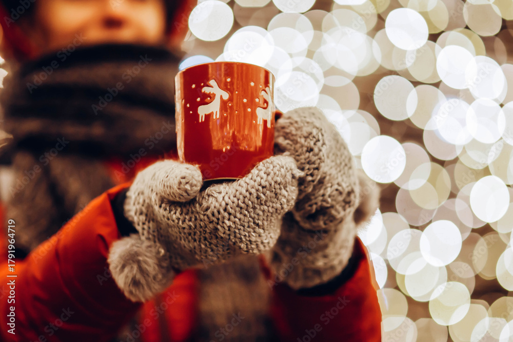 custom made wallpaper toronto digitalYoung woman in winter gloves holding a mug of hot tea or wine outdoor, Christmas lights in the background