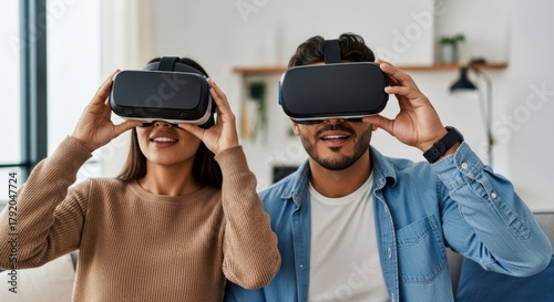 Young couple wearing virtual reality headsets, enjoying immersive gaming experience together in a cozy living room, showcasing modern technology and entertainment