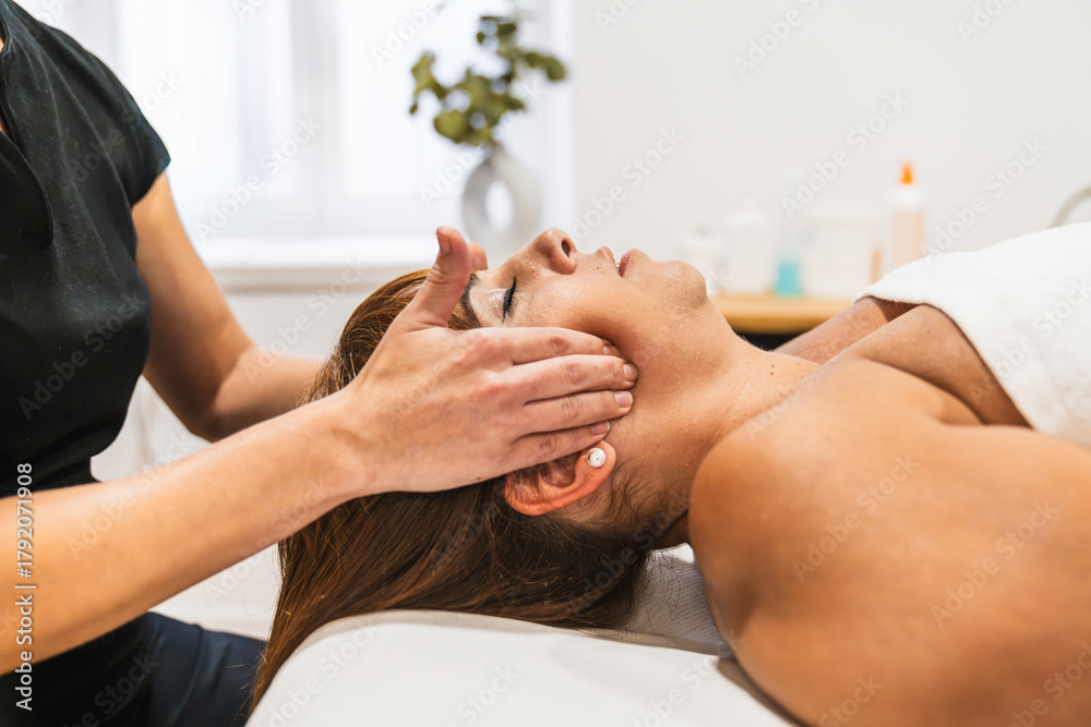 Obraz premium Physiotherapist performing a therapeutic massage on a woman's temporomandibular joint, treating jaw pain and promoting wellness