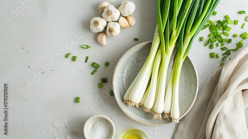 Dish of sautéed spring onions with garlic and olive oil, set on a clean kitchen counter.