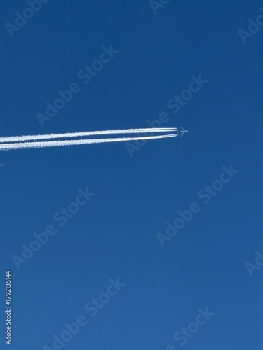 Airplane in the blue sky with contrails.