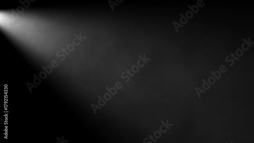 White light beam from top left spotlight effect shining through atmospheric smoke or dust particles on a dark black background with copy space