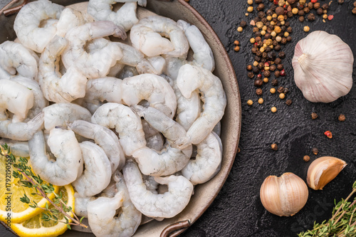 Εκτύπωση καμβά Raw peeled shrimp prawn with lemon and thyme in a metal pan on a textured black background