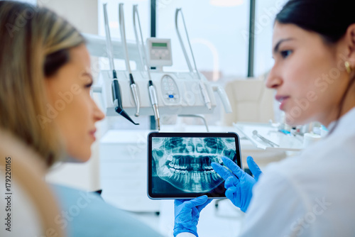 Bild auf Leinwand Dentist explaining dental X-ray images on a digital tablet to a patient during consultation at a modern dental clinic