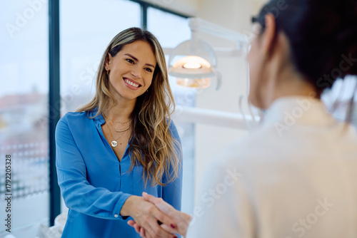 Фотография Smiling woman shaking hands at dental clinic, symbolizing trust, satisfaction, a