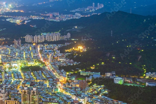 Illuminated cityscape at dusk with mountainous backdrop