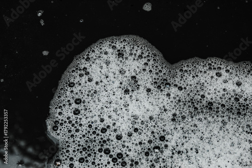 white soap foam texture with small and large air bubbles spread across the surface of the water