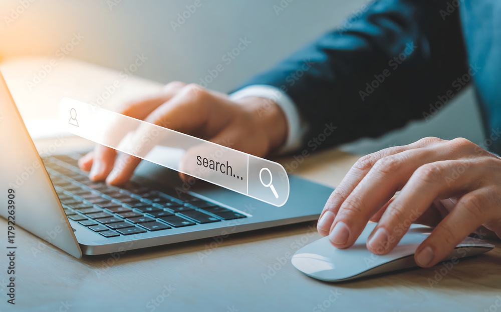 Fototapeta premium A person in a suit types on a laptop, with a search bar overlayed, indicating online research, digital marketing, and information gathering