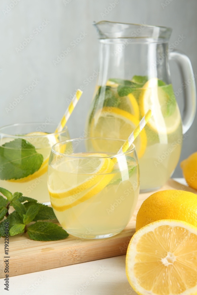 Fototapeta premium Fresh lemonade in glasses, jug, lemons and mint on white table, closeup