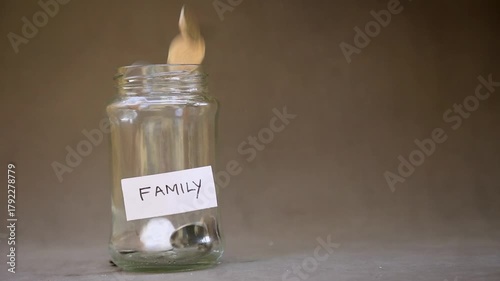 Slow Motion of Coins Dropping into Saving Glass Jar Labeled 