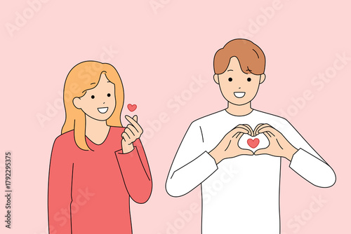 Smiling pair making heart gesture against soft pastel backdrop