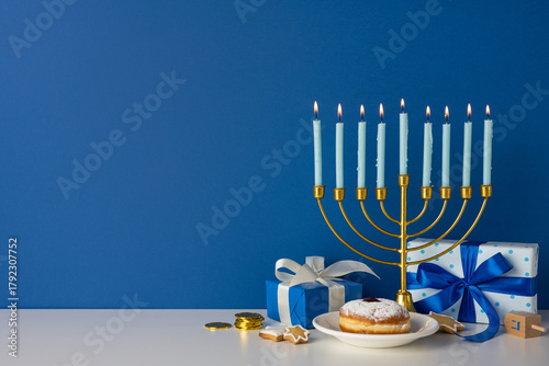 Photos A golden menorah with lit candles sits beside blue gift boxes, a plate with a pa