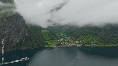 Tour boat full of people glides past scenic Undredal fjord landscape, drone footage Norway