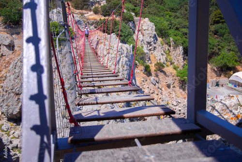A close-up view of the suspension Bridge stretching over the sea and cliffs. Thrill Ride for Tourists