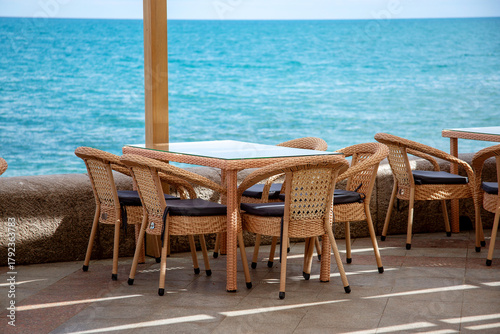 Wicker tables and chairs of an outdoor cafe by the sea. Cozy Restaurant on the seafront or oceanfront