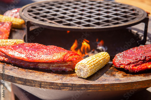 A piece of meat and ears of corn are grilled. Barbecue outside in a local cafe on an open fire