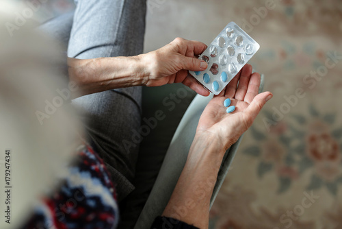 Senior woman taking her medication at home, close-up of hands
