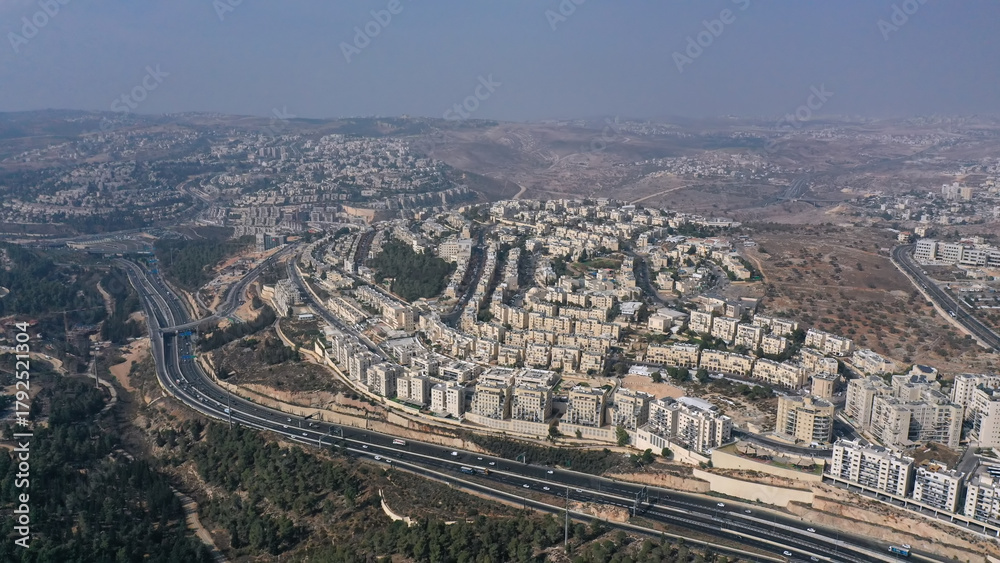 Obraz premium Aerial view of Highway 1 and Ramat Shlomo JerusalemA sweeping view of Ramat Shlomo’s dense residential blocks rising above the main Jerusalem–Tel Aviv highway.