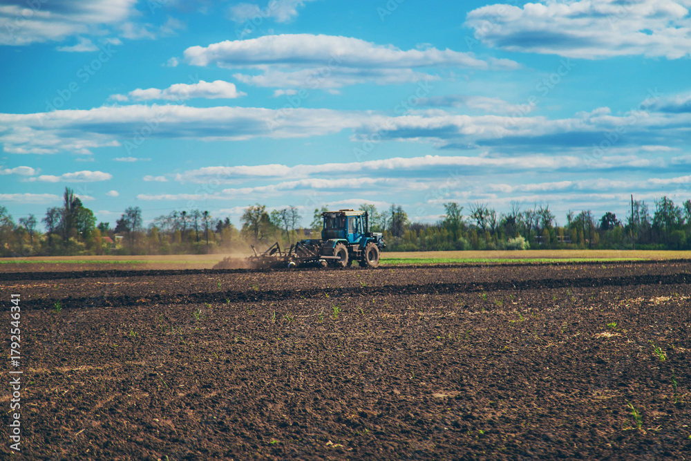 Fototapeta premium The tractor plows the soil in the field. Selective focus.