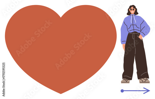 Woman in hoodie and wide-leg pants posed next to a giant red heart and directional arrow. Ideal for concepts thumbs up love, direction, confidence, self-expression, individuality, relationships