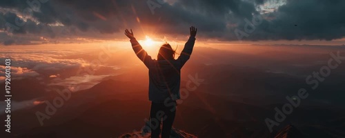 A person standing on a mountain peak at sunrise, wearing a hoodie, full body visible from a distance, looking confidently at the horizon