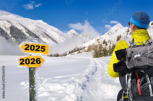 view on back of a hiker looking a post opposite directionnal 2025 and 2026 in the snowy mountain