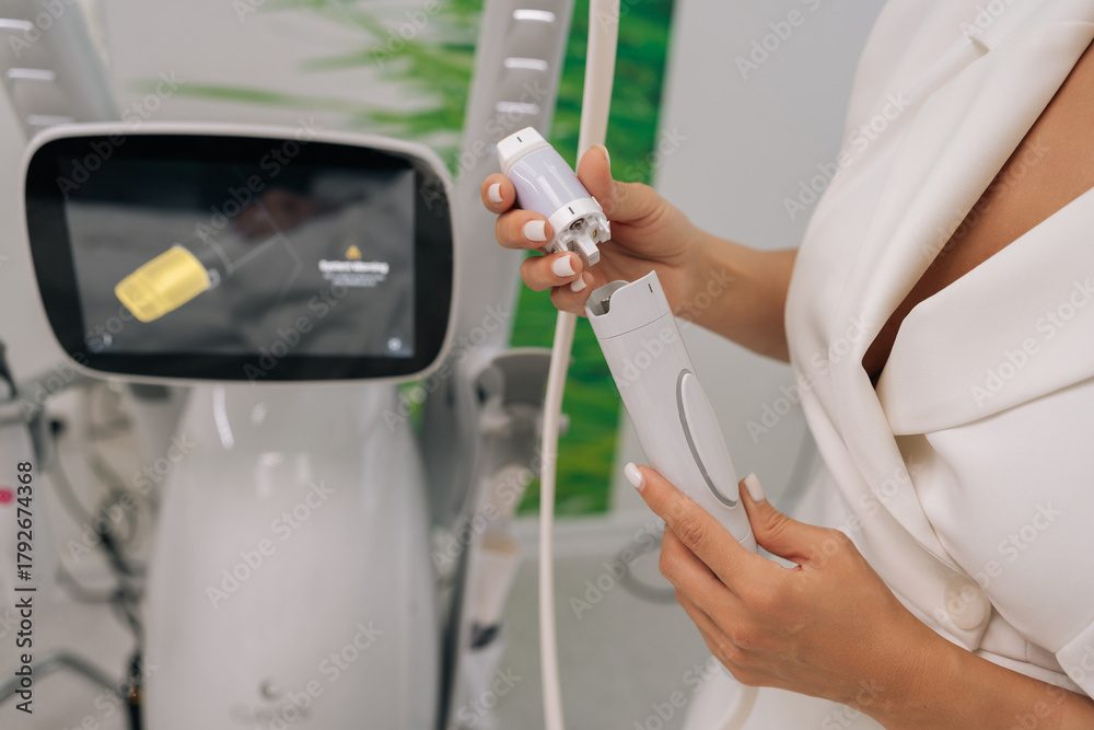Fototapeta premium Close-up of professional cosmetologist connecting specialized microneedle device, offering innovative beauty procedures and anti-aging solutions in modern aesthetic clinic.