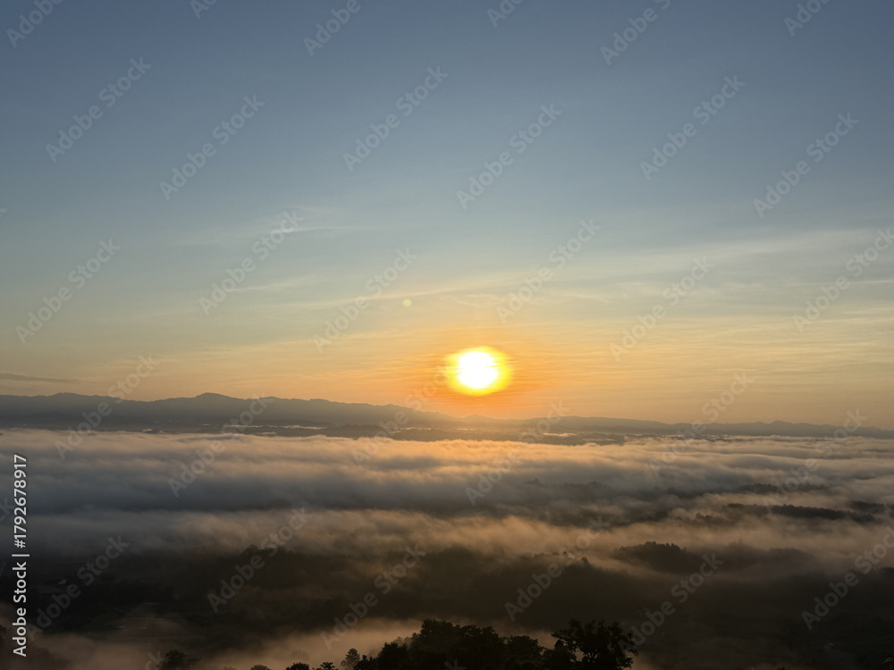 Fototapeta premium Sunrise over a sea of clouds with distant mountains