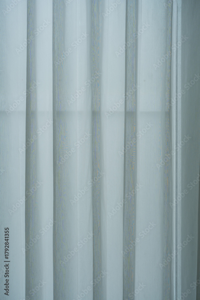 Obraz premium Sheer white curtains and a heavier, darker curtain partially drawn, allowing soft light to filter through.