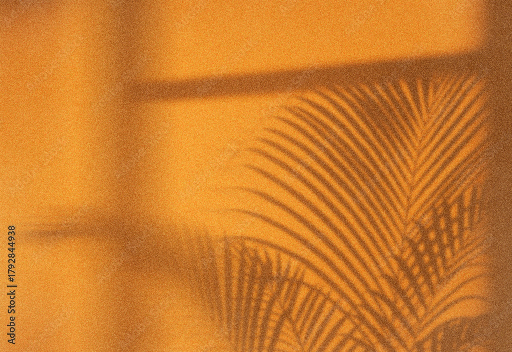 Fototapeta premium Close-up of orange tropical palm fronds bathed in soft ambient light, revealing an abstract leaf pattern with moody shadows, background texture for nature, travel, wellness decor.