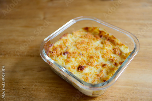 Golden Baked Pasta in Glass Dish on Wooden Table.