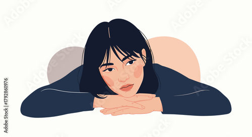 A thoughtful young woman with dark hair rests her chin on her hands.