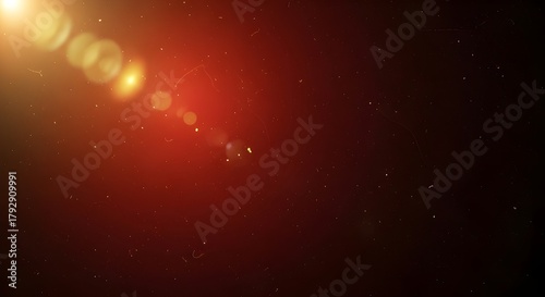 A bright golden lens flare emanates from the upper left, casting warm light and bokeh onto a dark red textured surface.