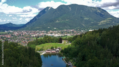 Aerial view of almsee lake and garmisch-partenkirchen town nestled in forested mountains under a summer sky