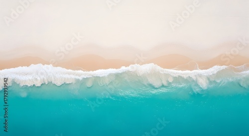 Drone view of a white beach with a light blue sea, as if divided into two sides, the sea side and the beach side.